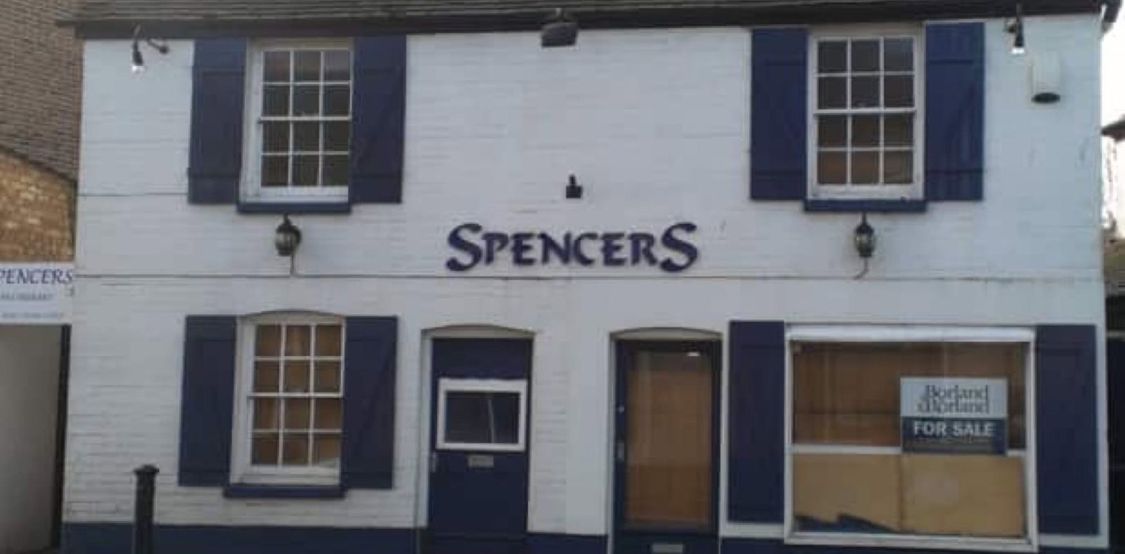Shop frontage before: painted brick, shutters and boarded window